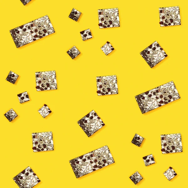 チョコレートバー全体を噛み 黄色の背景にナッツやドライフルーツと2つの部分に分割されたシームレスな定期的な創造的なパターン 布に印刷 包装紙 — ストック写真