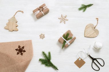 El yapımı Noel hediyesini hazırlamak ve Noel ve yeni yıl için sevgiyle hediye etmek. Firavun dalı, ladin dalları, kurdele, iplik, makas beyaz ahşap masada. Düz yatıyordu. Üst görünüm.