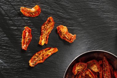 Kurutulmuş domatesler, İtalyan otları ve baharatlarıyla koyu arka planda fotokopi alanı, üst manzara. Ev yapımı kurutulmuş sebze..