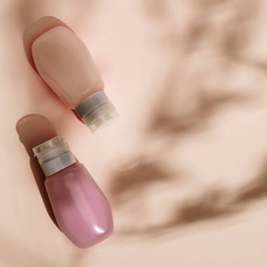 Krem, jöle ve losyon için kozmetik tüp. Güzellik ürünleri paketi, bej renkli arka planda sert gölgeli plastik kaplar, tek renkli görüntüler. Üst görünüm.