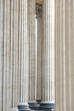 Arka plan olarak yüksek mermer sütunlar, klasik tarzda mimari tasarım. Uzayda sütunların mimari deseni. Tek renkli fildişi beyaz renk. Dikey resim.