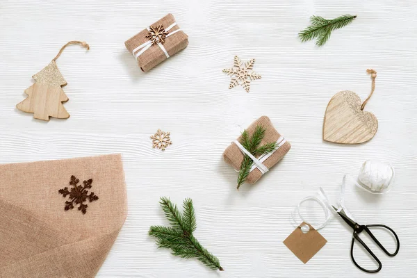 El yapımı Noel hediyesini hazırlamak ve Noel ve yeni yıl için sevgiyle hediye etmek. Firavun dalı, ladin dalları, kurdele, iplik, makas beyaz ahşap masada. Düz yatıyordu. Üst görünüm.