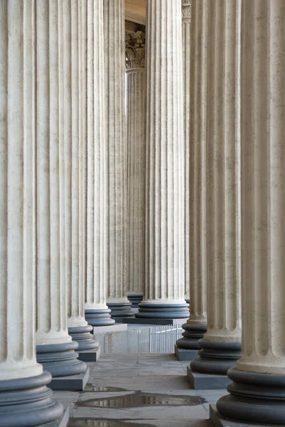 High marble columns as background, architectural design in style of classicism. Architectural pattern of pillars in space. Monochrome ivory white color. Vertical image.