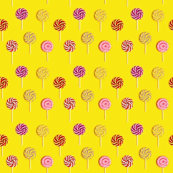 黄色の紙の背景にスティック上のストライプと甘い丸いキャンディーのループとシームレスなパターン 色キャンディクリエイティブ — ストック写真