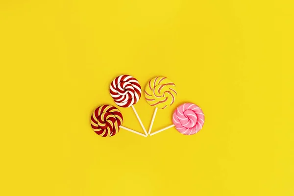 Słodkie Okrągłe Cukierki Lizaki Paskami Patyku Żółtym Tle Papieru Kreatywna — Zdjęcie stockowe