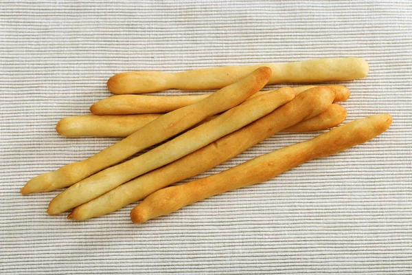 Tasty dry bread Italian grissini on light fabric. Grissini lies on tablecloth. Horizontal format. Top view. Copy space.