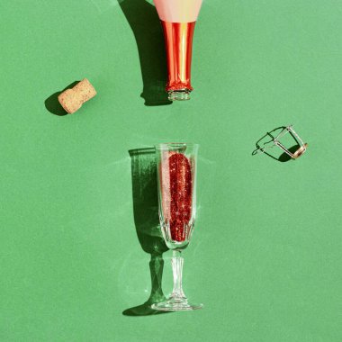 Şampanya bardağı ve parlak kırmızı pullu şişe, güneş ışığının gölgeleriyle ışıl ışıl şenlikli içecek. Yeni yıl ya da Noel partisi kutlaması. En düşük bileşim