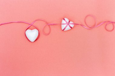 Beyaz Kalpler, canlı mercan arka planında pembe kurdele. Sevgililer Günü geçmişi. Aşk konsepti.