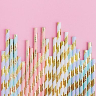 Pembe arka planda altın çizgili ve fotokopi alanı olan pipetler içen parlak kağıt. Parti ya da doğum günü kavramı. Düz yatıyordu. Üst Görünüm.