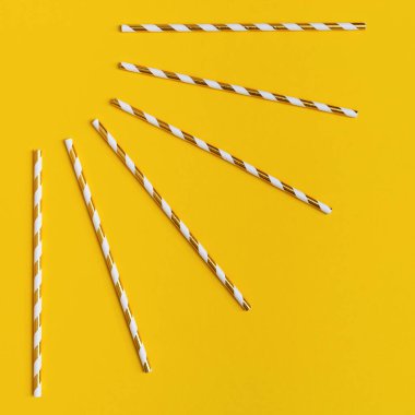 Parlak kağıt beyaz ve altın şeritli pipetler içerek sarı arka planda fotokopi alanı ile. Tatil ya da kutlama kavramı. Düz yatıyordu.