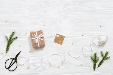 El yapımı Noel hediyesini hazırlamak ve Noel ve yeni yıl için sevgiyle hediye etmek. Firavun dalı, ladin dalları, kurdele, iplik, makas beyaz ahşap masada. Düz yatıyordu. Üst görünüm.