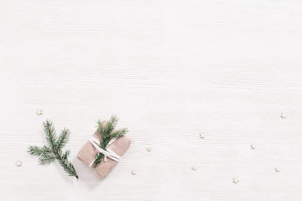 手作りの贈り物 クリスマスプレゼントボックスは コピースペース トップビュー フラットレイアウトと白い木製のテーブルの上に自然の緑のモミの枝を飾るクラフト布で包まれた — ストック写真