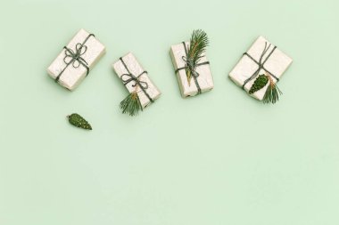 Noel hediyesi kutuları doğal köknar dalları ve pastel yeşil arka planda yeşil çam kozalakları ile süslenmiş. Kış kutlaması için bayram konsepti Yeni Yıl ve Noel