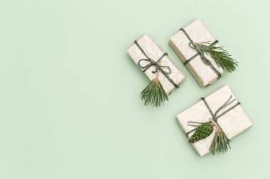 Noel veya Yeni Yıl kompozisyonu. Noel hediyesi kutuları, çam kozalakları, açık yeşil arka plandaki ladin dalları ve fotokopi alanı. Üst görünüm.