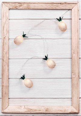 Beyaz ahşap üzerine altın rengi ananaslar gibi sicim ışıkları olan bir Noel arkaplanı. Kutlama süsü, yeni yıl perisi çelengi. Düz yatıyordu. Üst görünüm, alanı kopyala.