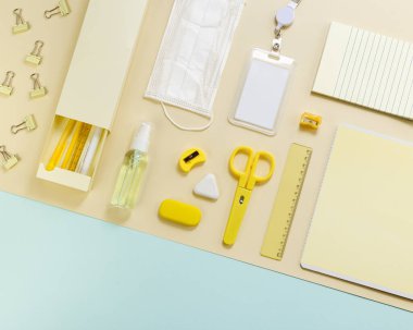 Ofis malzemeleri ve kişisel koruyucu ekipmanlarıyla yeni normal konsept çalışma masası okulu. Fotokopi defteri, kalem, kalem, cetvel, kalem kutusu, makas ile geometrik desen. Üst görünüm.