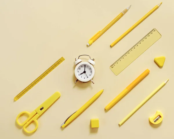 目覚まし時計午前8時 学校の概念に移動する時間を示しています 黄色のパステルカラーの時計や文房具の学校用品と創造的なフラットレイ — ストック写真