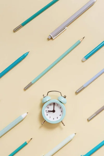 目覚まし時計午前9時 学校の概念に移動する時間を示しています ベージュ地に青いペンと鉛筆の時計と幾何学模様の創造的なフラットレイ — ストック写真