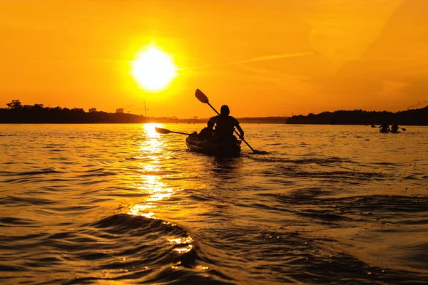 日没時にボートの中の人々のシルエット 男と女は川に乗ってボートに乗る 小さな家族旅行 メンバーが一緒に時間を過ごす 休息とリラックスしている — ストック写真