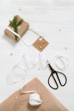 Kraft kumaşına sarılı Noel hediye kutusu beyaz ahşap masa üzerinde doğal yeşil köknar dalı fotokopi alanı, üst manzara, düz yer. Tatil için hazırlık