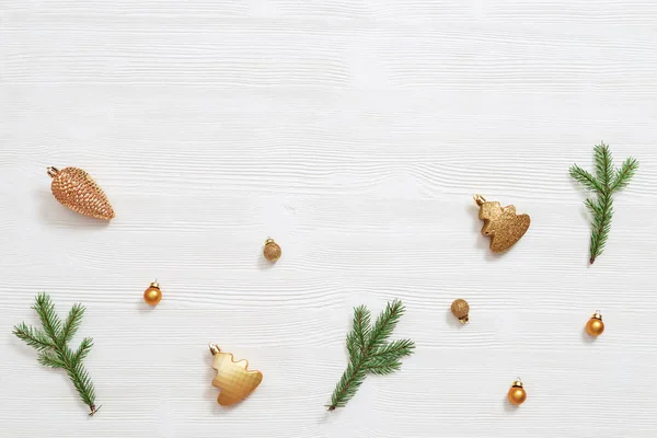 白い木の上に金色の小さなボールと自然の緑のモミの木の枝とクリスマスの背景 美しい新年と冬の休日の概念 平置きだ トップ表示 — ストック写真