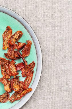 Kurutulmuş domatesler, İtalyan otları ve baharatlarıyla mavi arka planda fotokopi alanı, üst manzara. Ev yapımı kurutulmuş sebze..