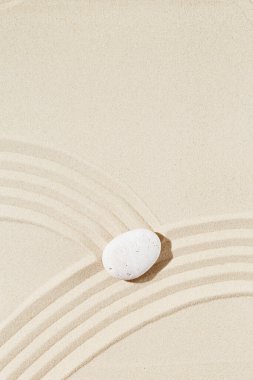 Kumda zen taşı olan estetik bir arka plan. Japon Zen Bahçesi 'nde, meditasyon ve sükunet için beyaz çakıl taşının etrafında eşmerkezli daireler çizilmiş. Yukarıdan görüntüle.