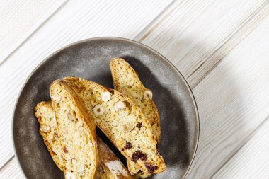 Geleneksel İtalyan bademli cantuccini kurabiyeleri gri tabakta. Beyaz ağaçlık masada ev yapımı tatlı bisküviler. Üst görünüm.