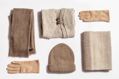 Sonbahar sıcak giysileri düz, örgü şapka, yün atkı ve süet eldivenler, bej kazak. Kadınlar sonbahar mevsiminde soğuk hava için örgü örerler. Üst görünüm.