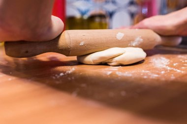 Un dolu hamuru şekillendirmek için mutfak raptiyesi kullanan eller.