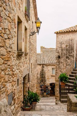 Peratallada, Katalonya - Eylül 2017: Peratallada 'nın ortaçağ kasabasında arka planda bir turist dükkanı bulunan Narrow Caddesi