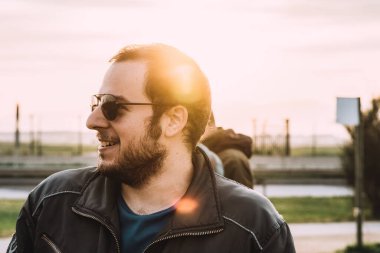 Havacı gözlüklü bir adam gülümsüyor, arkasında parlayan bir ışık.