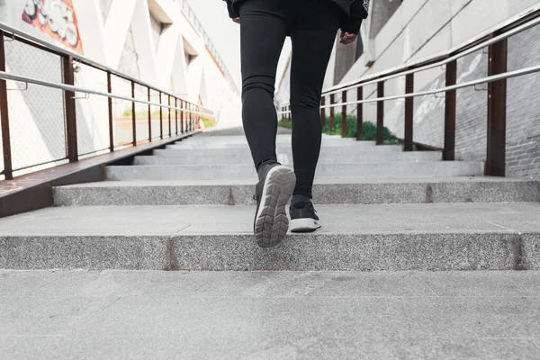 Legs of a man wearing sports tights walking up some stairs