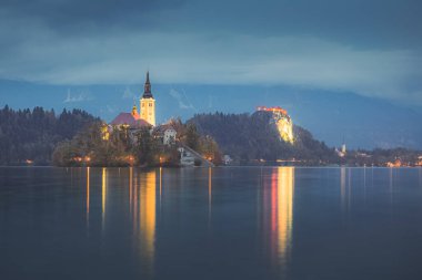 Slovenya 'nın Julian Alpleri kıyısındaki Bled Gölü' nde, Maria Bled Kalesi 'nin Hacı Kilisesi' nin alacakaranlık manzarası parladı..