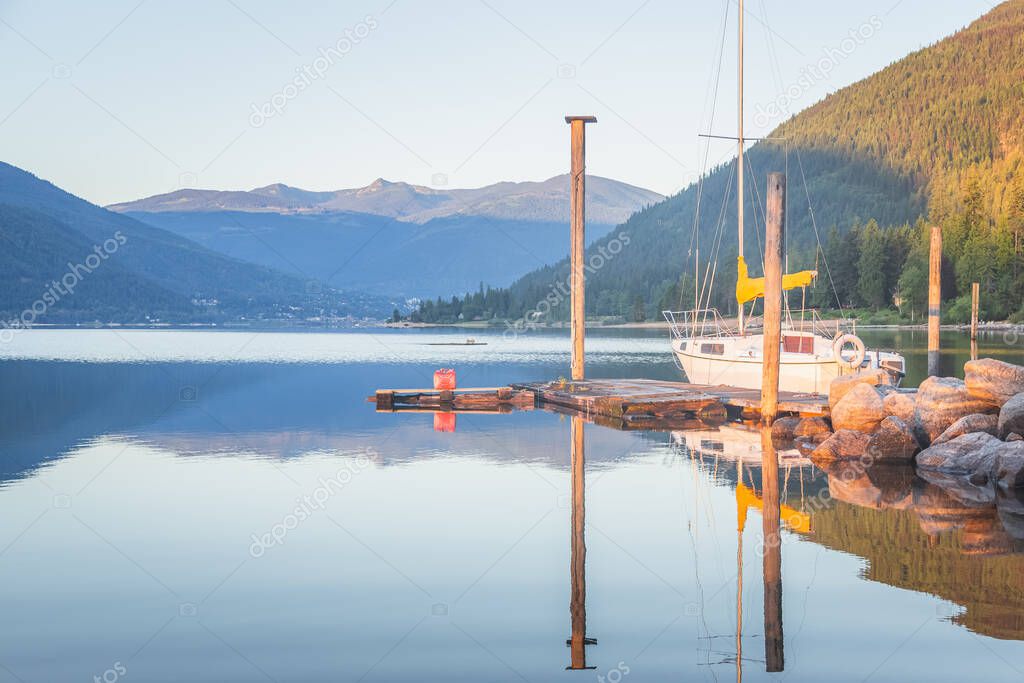 A beautiful, calm summer morning at sunrise on Kootenay Lake with views of Nelson, B.C., Canada