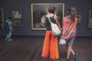Orsay Müzesi ziyaretçileri Manet 'in ünlü başyapıtı' Le Djeuner sur l 'herbe' ye bakıyorlar.