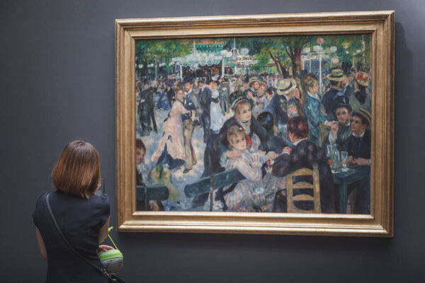 A visitor to the Musee d 'Orsay looking at Renoir' s famous masterpiece 'Bal du moulin de la Galettei'
