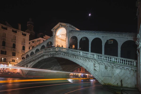 水上バスは イタリアのヴェネツィアにある有名なリアルト橋の下のように夜に光の跡を残します — ストック写真