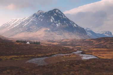 İskoçya 'daki Glencoe' da bir dağ manzarasına karşı ıssız bir kulübe..