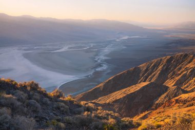 Gün batımında gün batımında altın güneş ışınları ya da Badwater Havzası 'nın çöl manzarası üzerinde Dantes View' den gelen tuzlu düzlükler Ölüm Vadisi Ulusal Parkı, Kaliforniya, ABD.
