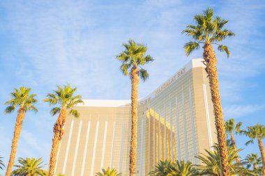 Las Vegas, Nevada, ABD 'de güneşli bir günde palmiye ağaçları olan Mandalay Körfezi Oteli ve Kumarhanesi' nin altın cephesi..