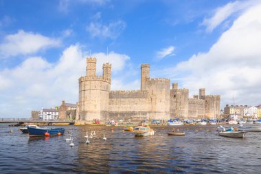 The historic medieval Caernarfon Castle on the River Seiont on a summer day in North Wales, UK. clipart