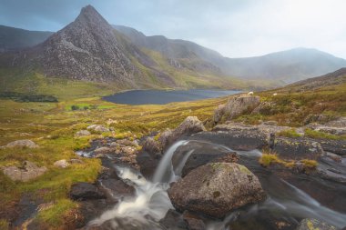 Tryfan tepesi, Llyn Ogwen ve Kuzey Galler 'deki Snowdonia Ulusal Parkı' ndaki vadiyle birlikte hüzünlü, dramatik bir şelale manzarası.