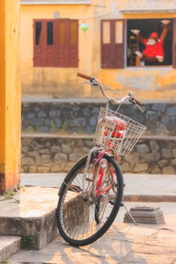 Vietnam 'ın Hoi An kasabasında ön sepeti olan tek başına klasik kırmızı bir bisiklet..