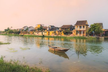 Thu Bon Nehri 'nde, eski Hoi An kasabasında altın bir günbatımında geleneksel bir Vietnam teknesi..