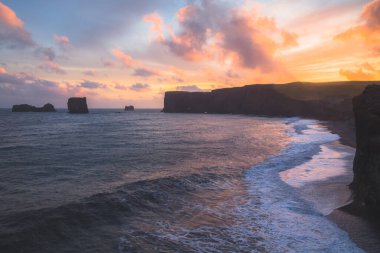 Canlı, renkli gün batımı ya da Güney İzlanda 'daki Dyrholaey' de deniz manzarası ve kıyı şeridi..