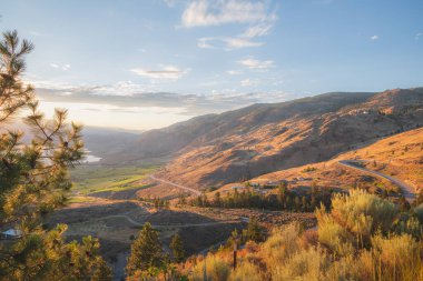 Osoyoos, İ.Ö. 'deki Okanagan Vadisi üzüm bağlarının ve meyve bahçelerinin üzerinde gün batımı altın ışığı. Kanada, şarap ülkesi çöl manzarası.