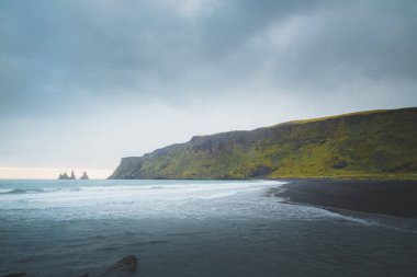 Reynisdrangar 'ın atmosferik deniz manzarası. Reynisfjara' daki siyah kumsal sahili. Güney İzlanda 'nın Vik kıyı balıkçı köyü..