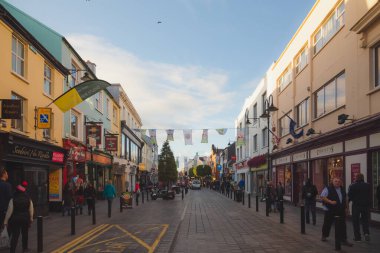 Busy, bustling main street with tourists and locals in the colourful Irish town of Killarney, Ireland on a summer evening. clipart
