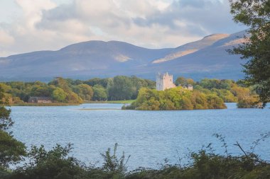 Killarney Ulusal Parkı 'ndaki Lough Leane Gölü' ndeki tarihi Ortaçağ Ross Kalesi 'nin manzaralı günbatımı manzarası, Kerry County, İrlanda.